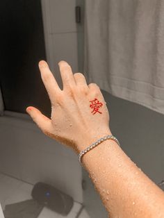 a woman's hand with a red tattoo on her left wrist and the word love written in chinese