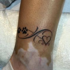 a dog paw and heart tattoo on the ankle