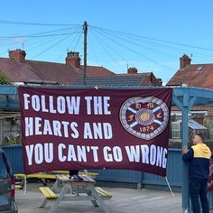 a man standing next to a sign that says follow the hearts and you can't go wrong