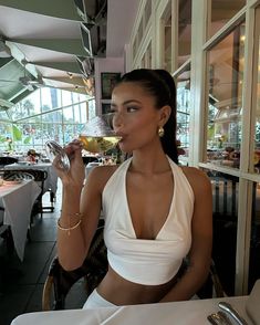 a woman sitting at a table with a glass of wine in her hand and looking into the distance