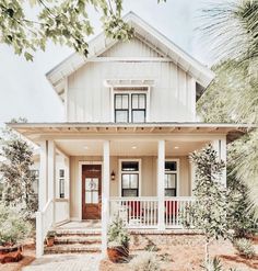 a white house with red accents on the front porch and steps leading up to it