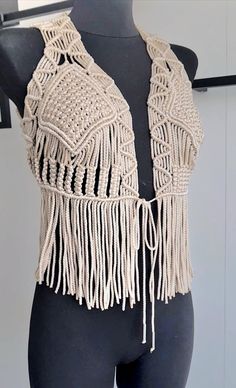 a mannequin wearing a white crochet vest with fringes on it