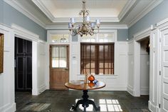 a dining room with a chandelier hanging from the ceiling and two vases on top of a table