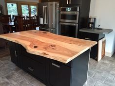 a kitchen island made out of wood in the middle of a room with stainless steel appliances