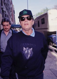 a man walking down the street wearing sunglasses and a sweatshirt with a bear on it