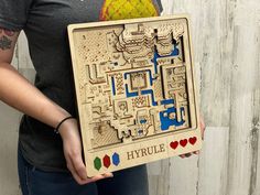 a woman holding up a wooden puzzle that says hyrule on the front and back