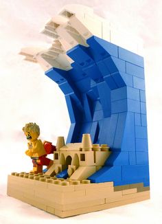 a lego model of an ocean wave with a man standing on the beach next to it