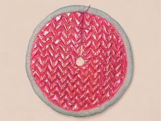 a pink and grey circular object on a white surface with an orange string attached to it