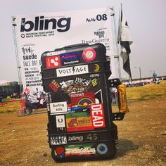 a cart with stickers on it sitting in the middle of a dirt field next to a billboard