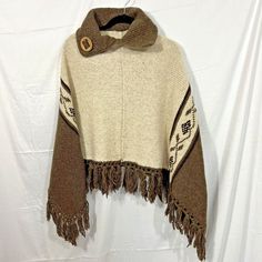 "In good preowned condition. Measures 27\" from top back of collar to bottom of fringe (shortest length) and 33\" from shoulder to bottom of fringe (longest length) measurements are approximate." Beige Fringe Shawl Poncho, Beige Fringed Poncho Shawl, One Size Brown Fringe Poncho, Brown Fringe One Size Poncho, Brown One Size Poncho With Fringe, Traditional Fringe Poncho For Fall, Traditional Fall Poncho With Fringe, One Size Fringe Shawl Cape, One Size Fringe Cape Shawl