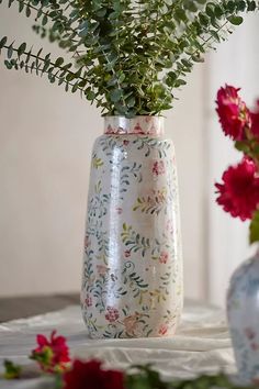 two vases with flowers in them sitting on a white table cloth covered tablecloth