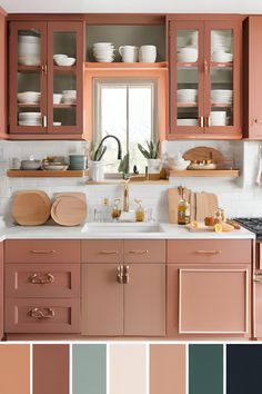 a kitchen with pink cabinets, white counter tops and lots of dishes on the shelves