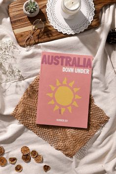 a pink book sitting on top of a bed next to a cup and saucer