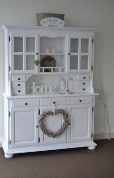 a white hutch with a heart wreath on top