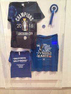 an assortment of t - shirts are displayed in a display case with ribbons and badges