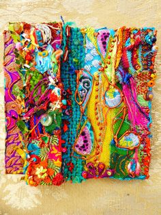 three different colored pieces of fabric with beads and bead work on them, sitting on a lace covered surface