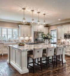 a large kitchen with white cabinets and marble counter tops, an island in the middle