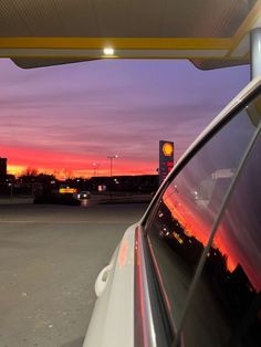 the sun is setting at an empty gas station