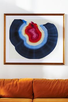 a painting hanging on the wall above a couch in a living room with an orange sofa