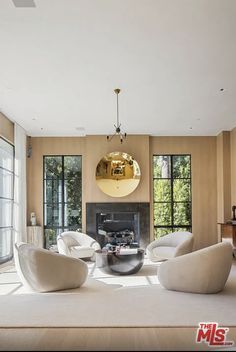 a living room with large windows and white furniture in the center, surrounded by wooden flooring