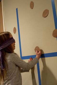 a girl is painting the wall with blue tape and some circles on it in an empty room