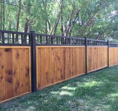 a wooden fence with metal railings in the grass