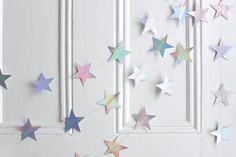 there are many stars hanging on the door and one is pink, blue, yellow or green