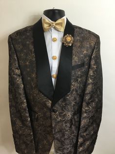 Our new chocolate and gold floral print tuxedo will be an outstanding addition to any man's wardrobe. Black satin lapels will bring a ray of elegance to your outfit. This tuxedo includes beautiful button covers, a matching carnation boutonnière, matching cufflinks, and a matching bow tie with a diamond center display.  For additional sizes, please contact the seller. Black Suits With Gold Accents Men, Black Suit With Gold Accents, Carnation Boutonniere, Mens Wedding Suits, Shawl Collar Tuxedo, Gold Suit, Wardrobe Black, Chocolate Gold, Tuxedo Wedding