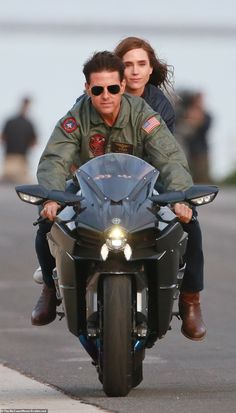 a man riding on the back of a motorcycle next to a woman