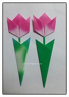 three pink and green paper tulips with one folded in the shape of an arrow