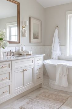 a white bathroom with a tub, sink and mirror