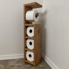 a wooden shelf with three rolls of toilet paper in it and one roll is on the floor