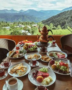 a table full of food with mountains in the background