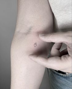 a small apple tattoo on the left side of the right arm, with an arrow in the middle