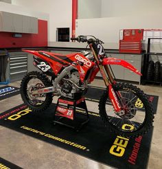 a red dirt bike on display in a garage