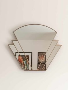 a mirror mounted to the side of a wall with three pictures hanging on it's sides