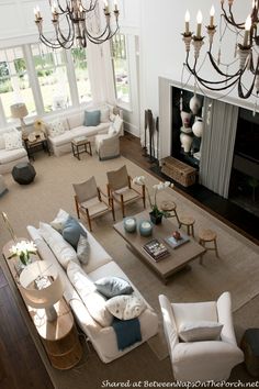 a living room filled with lots of furniture and a chandelier hanging from the ceiling