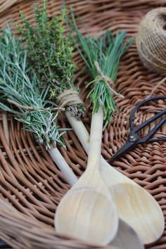 some herbs are sitting in a basket on the table next to scissors and twine