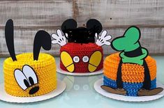 three mickey mouse cakes are sitting on top of each other, one is yellow and the other is red