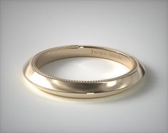 a gold wedding band with engraved engraving on the side and beading around the edge