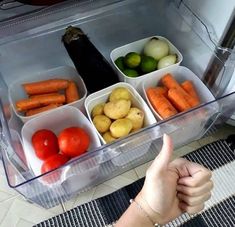 a person is giving the thumbs up sign in front of a refrigerator full of vegetables and fruits