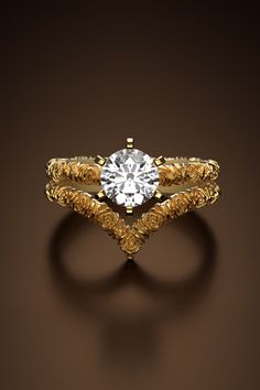 a gold ring with a diamond in the center on a brown background, it looks like an intricate design