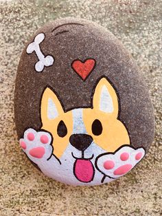 a painted rock with a dog on it's face and paw prints in the shape of a heart