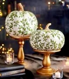 two white pumpkins sitting on top of gold candlesticks next to each other