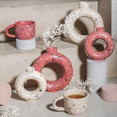 some pink and white vases sitting next to each other on the steps with coffee in them