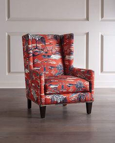 an upholstered red chair in front of a wall with white paneling and wood floors