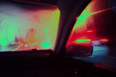 the rear view mirror of a car driving down a street with traffic lights at night