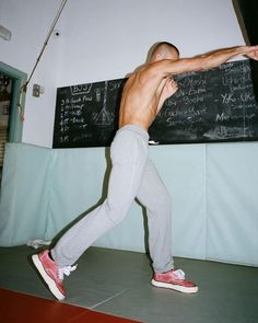 a shirtless man standing in front of a chalkboard