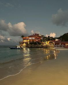 a beach with boats and houses on the shore at night, in front of an ocean