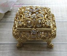 an ornately decorated box sitting on top of a wooden table next to a flower